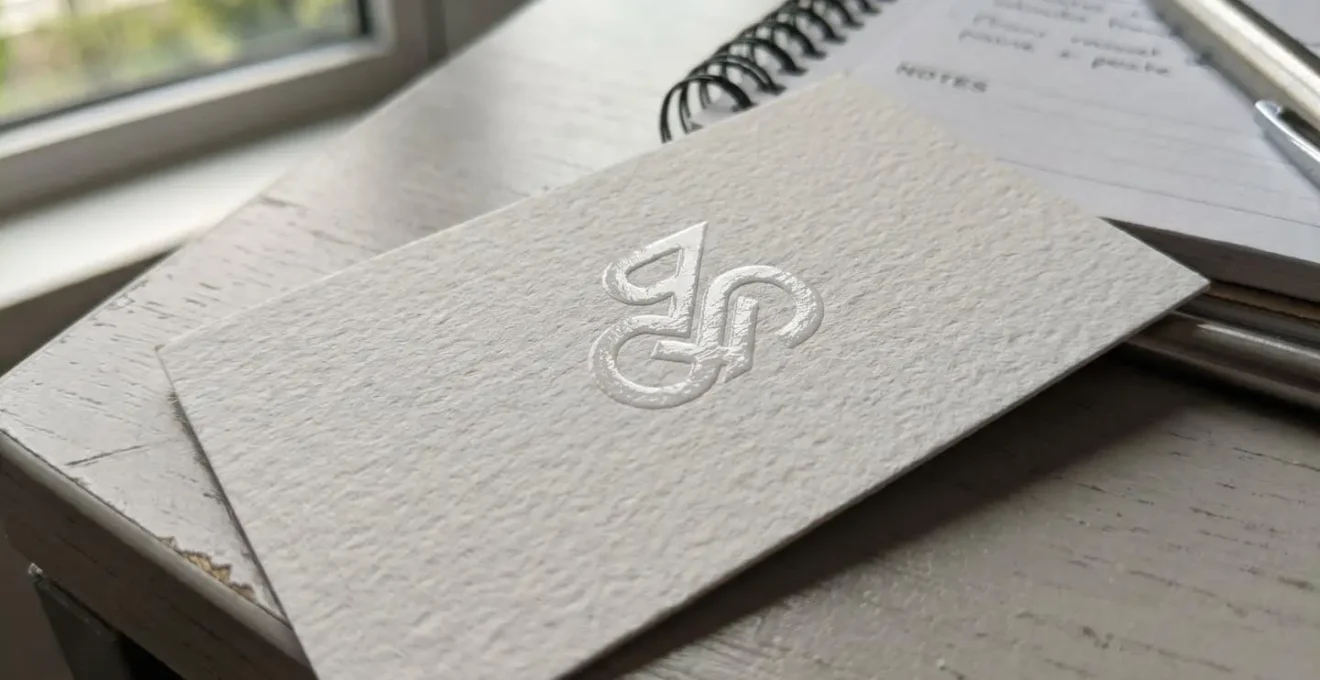 Gros plan d'une carte de visite avec logo en relief et vernis sélectif sur papier texturé, posée sur un bureau