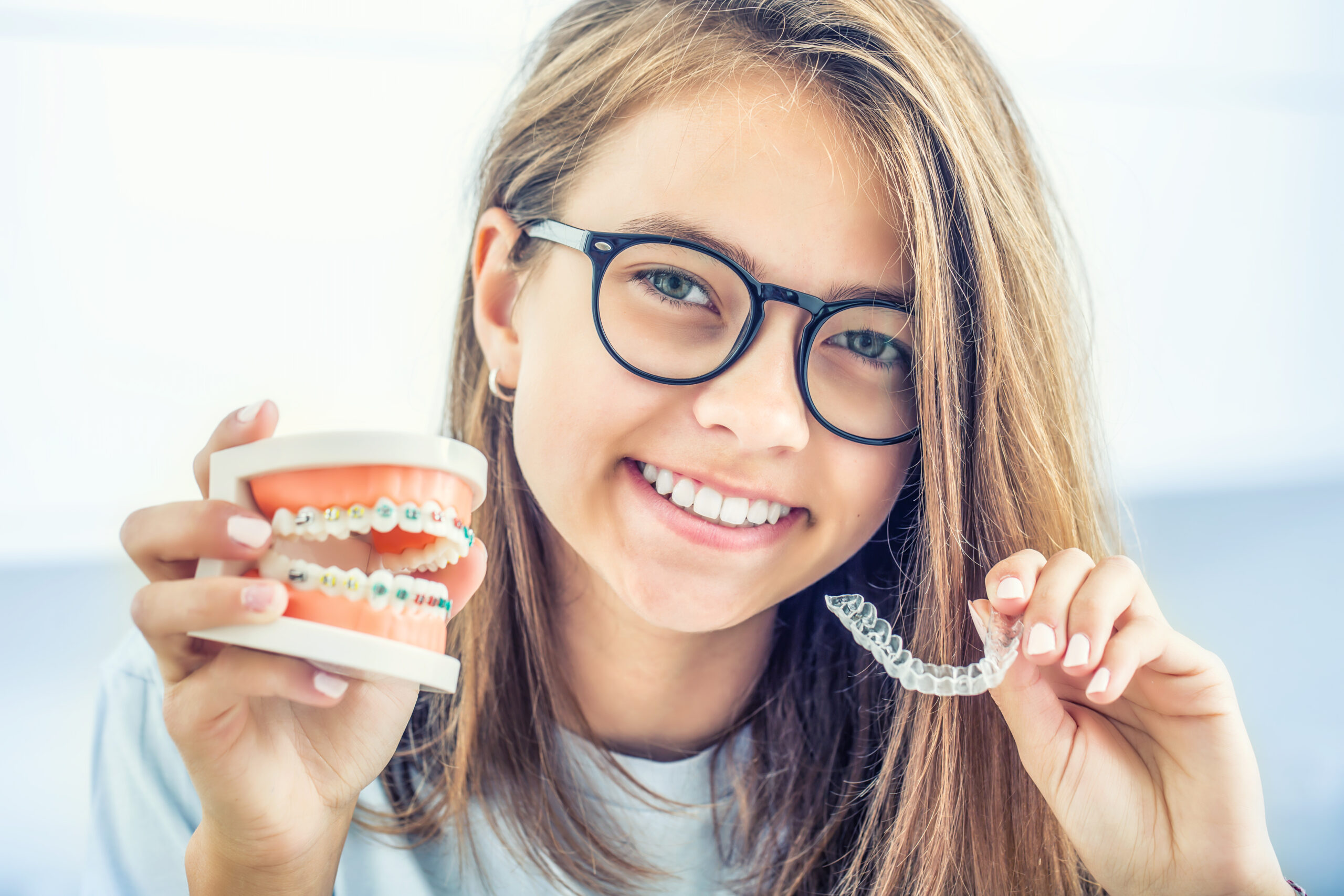 Gouttière transparente Invisalign et bague métallique photographiées côte à côte sur une surface blanche épurée